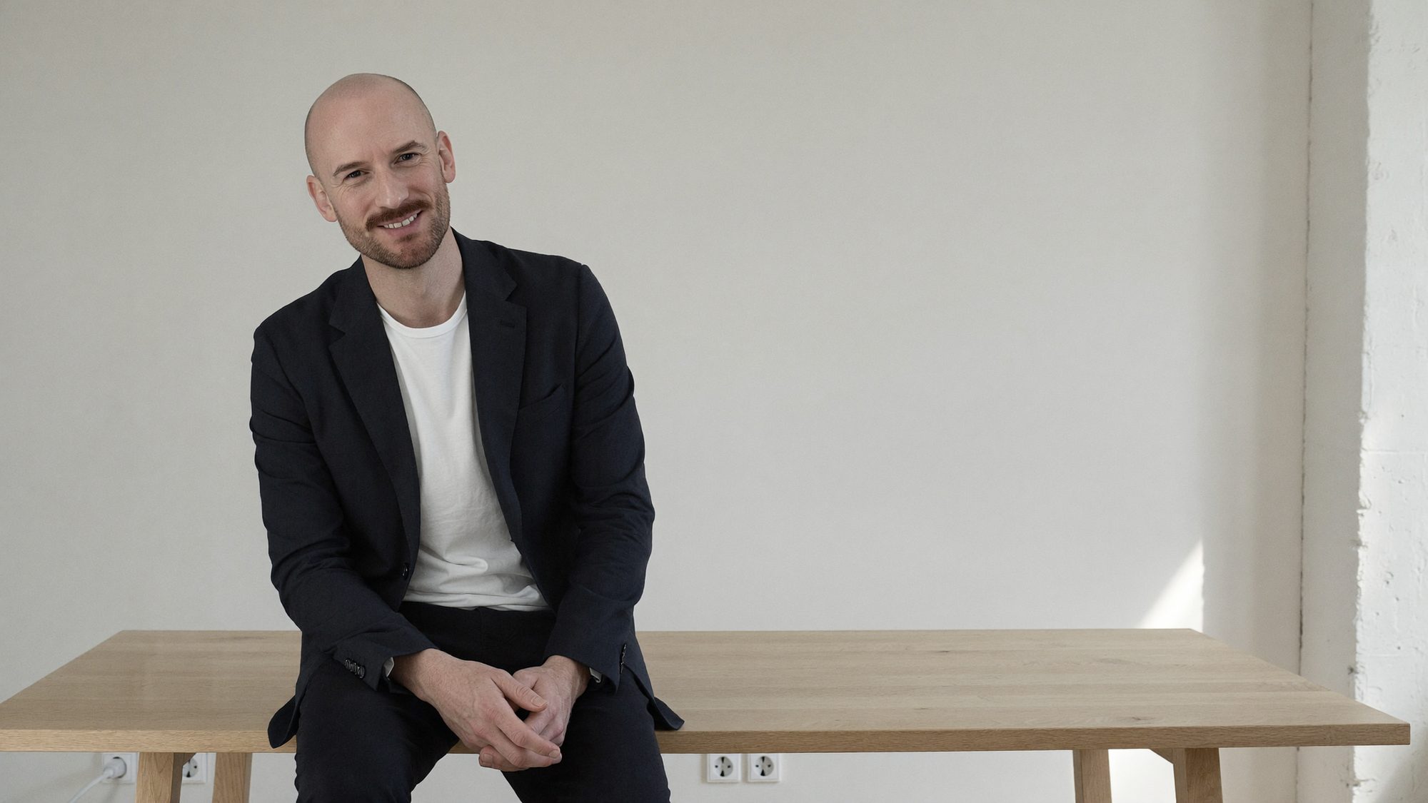 Martin Kunze, The Brand Scaler, sitzt auf einem Holztisch